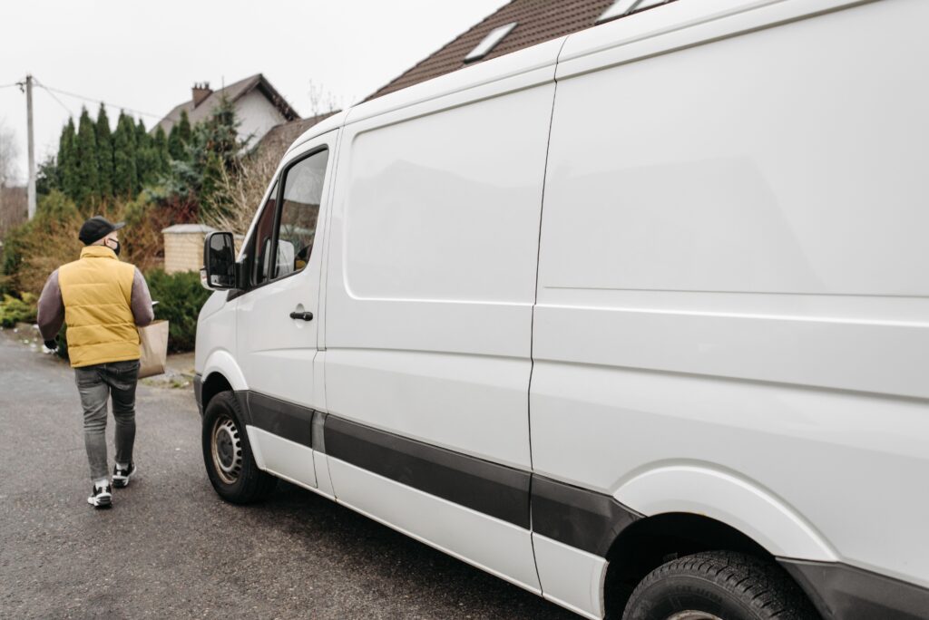 A delivery person carrying a package away from a delivery van outdoors, showcasing efficient logistics.